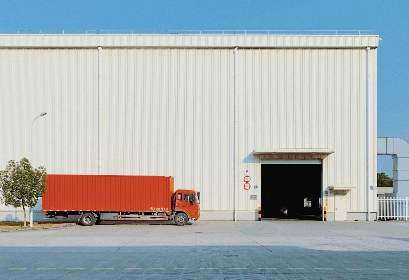 Modern distribution warehouse with an open loading bay and a delivery truck parked outside