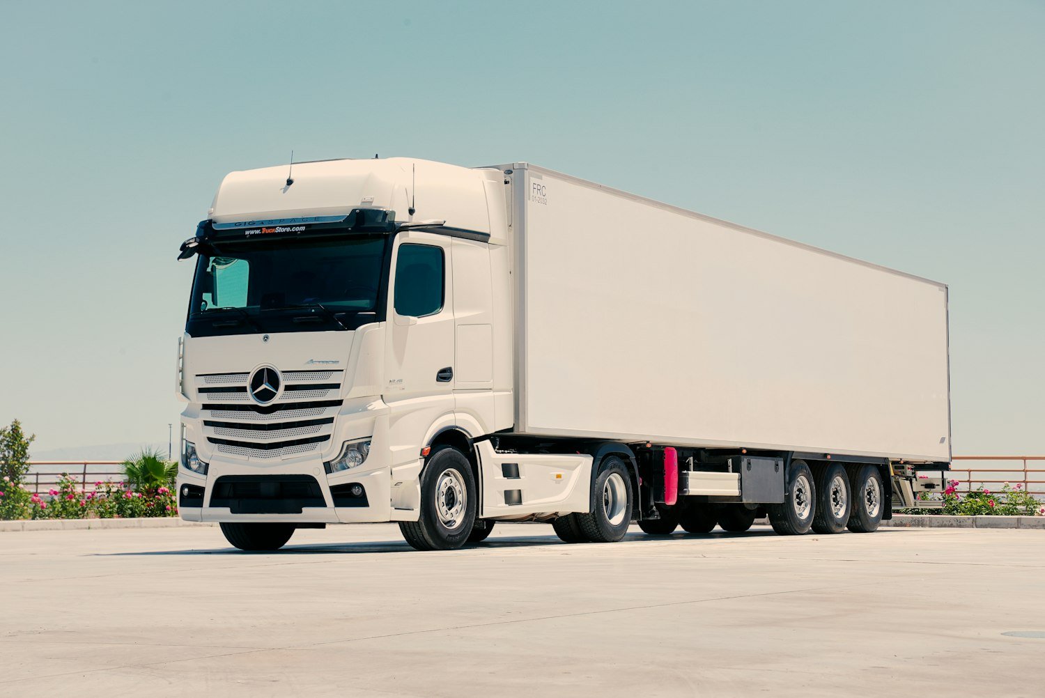 White freight truck and trailer parked at a distribution yard in warm evening light