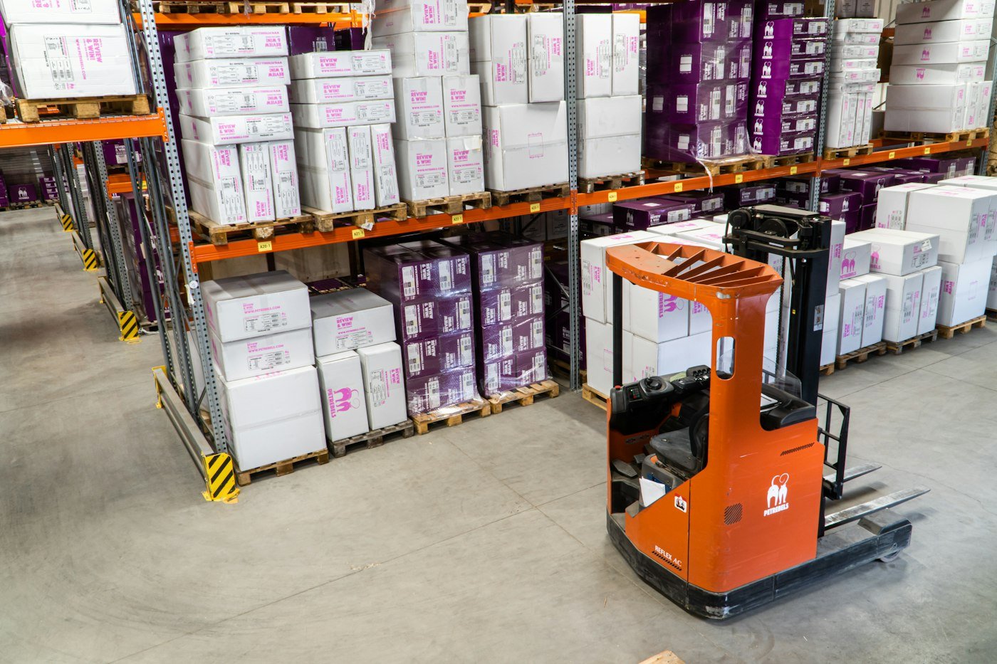 Forklift operating between stocked warehouse racks