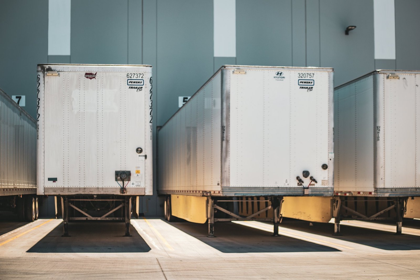 Semi-trailers backed into the loading bays of a modern distribution warehouse in warm afternoon light