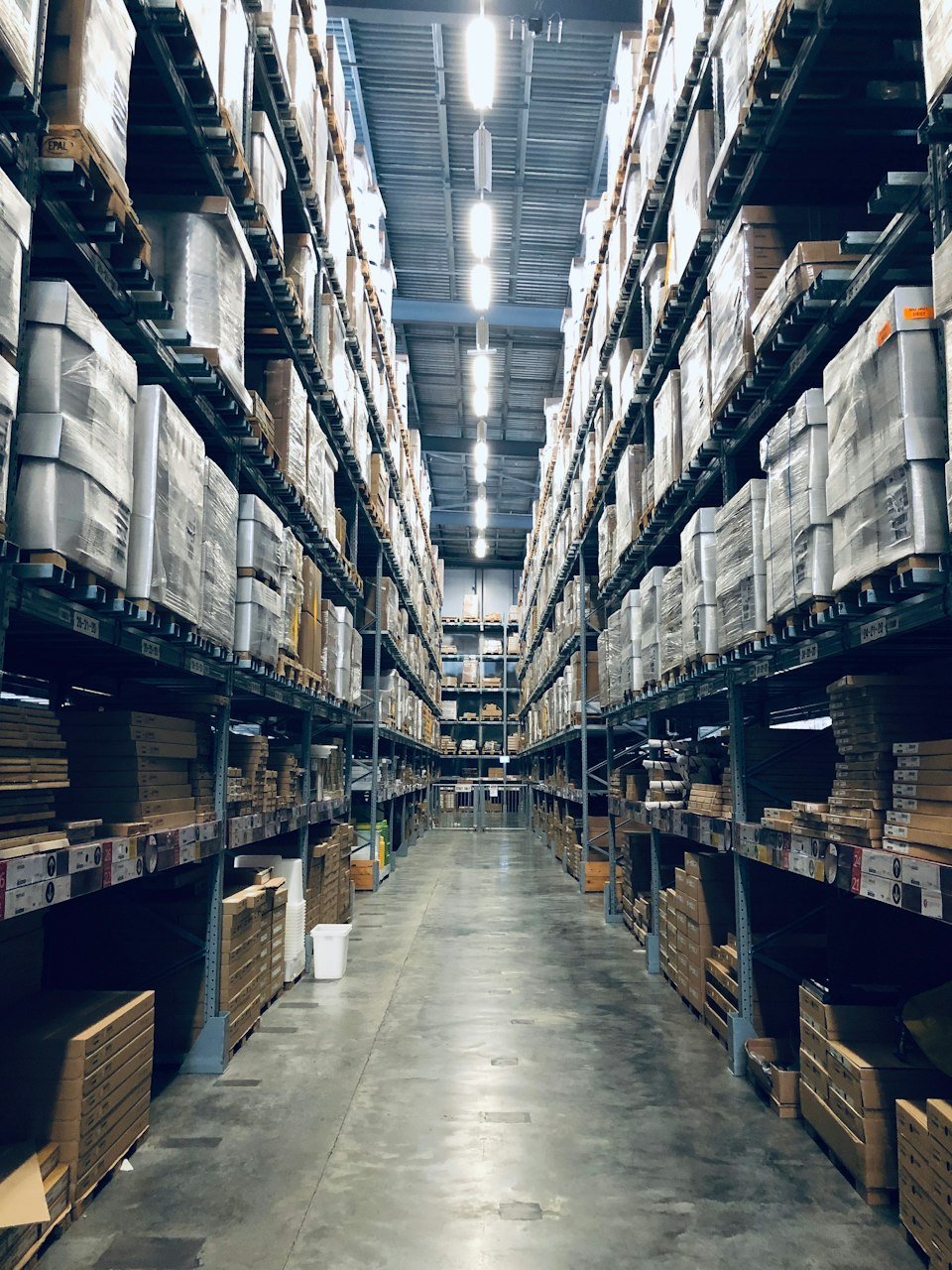 Long warehouse aisle lined with tall storage racks full of palletised inventory
